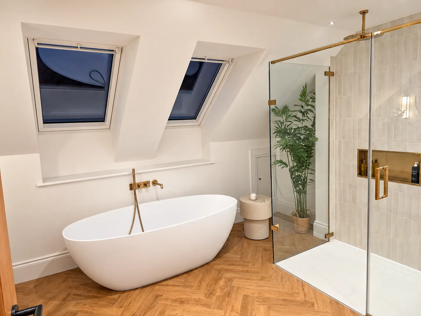 Bathroom with freestanding bath, twin skylights and brass-framed walk-in shower