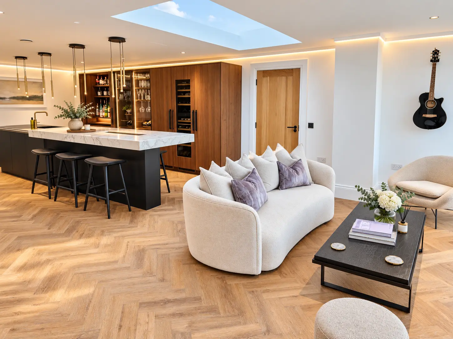 Open-plan bar room with marble island, walnut cabinetry, wine fridge and curved sofa beneath a skylight