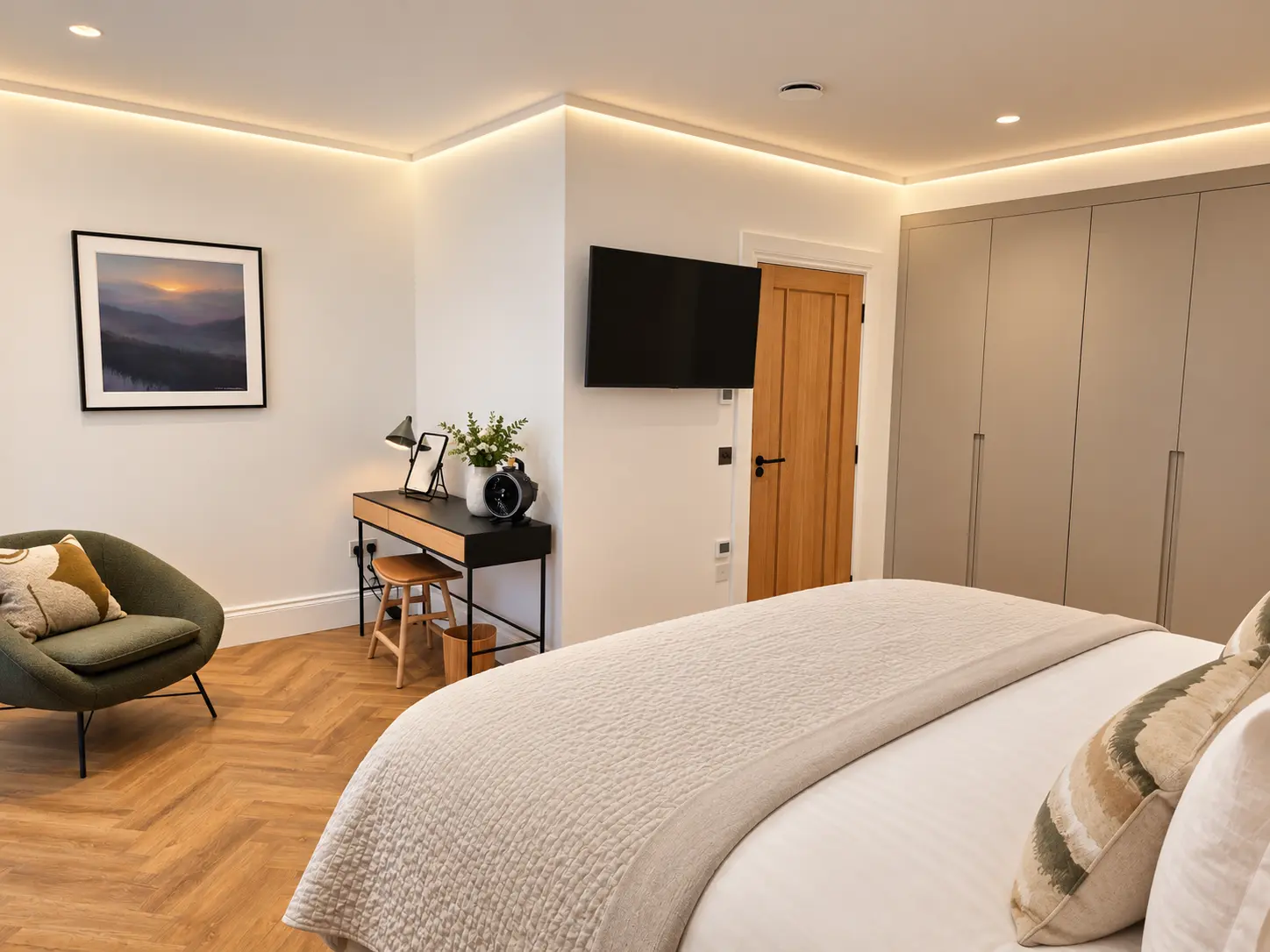 Calm bedroom with herringbone floor, fitted wardrobes, desk, armchair and wall-mounted TV