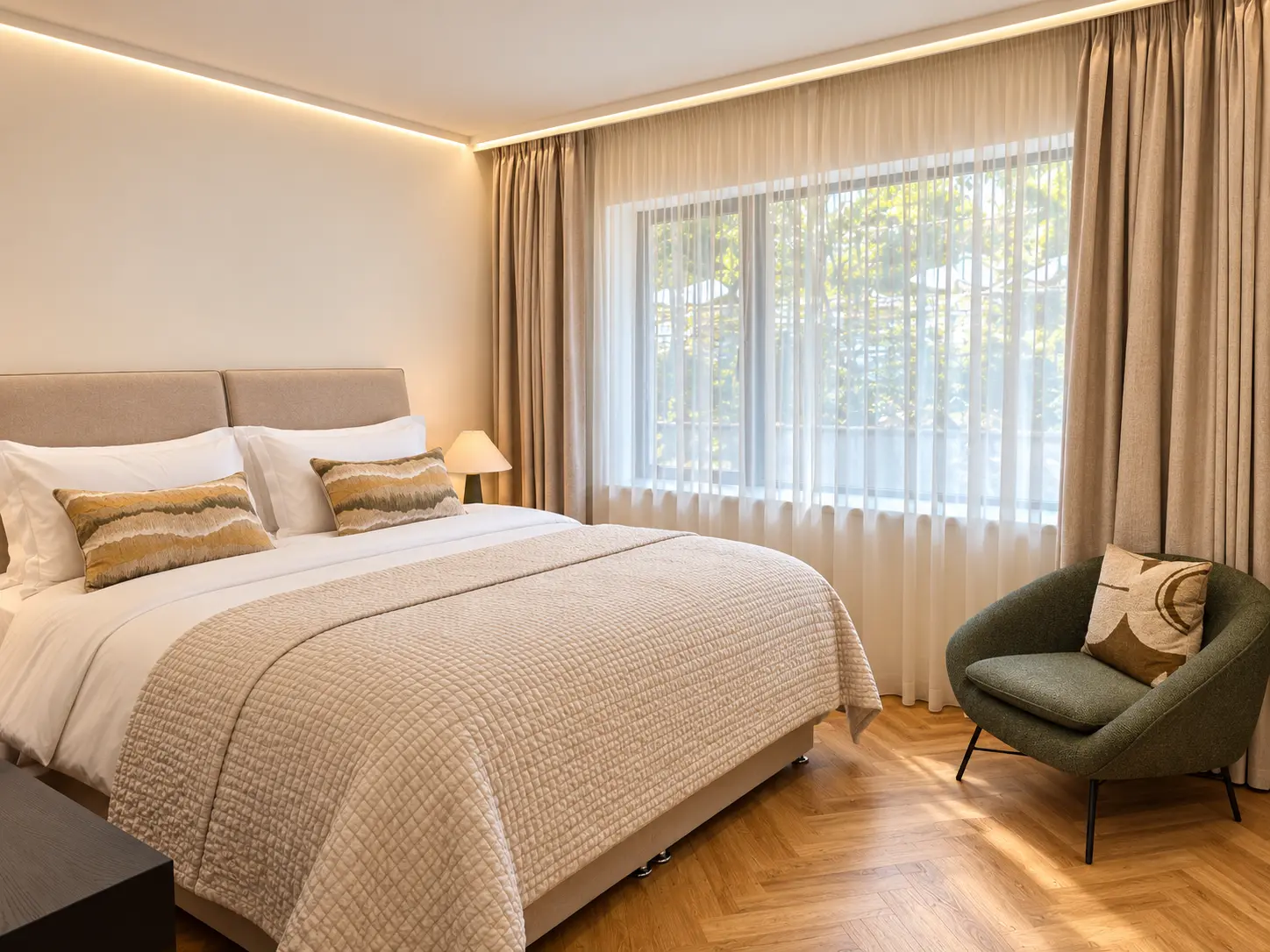 Double bedroom with upholstered headboard, green armchair and garden-facing window