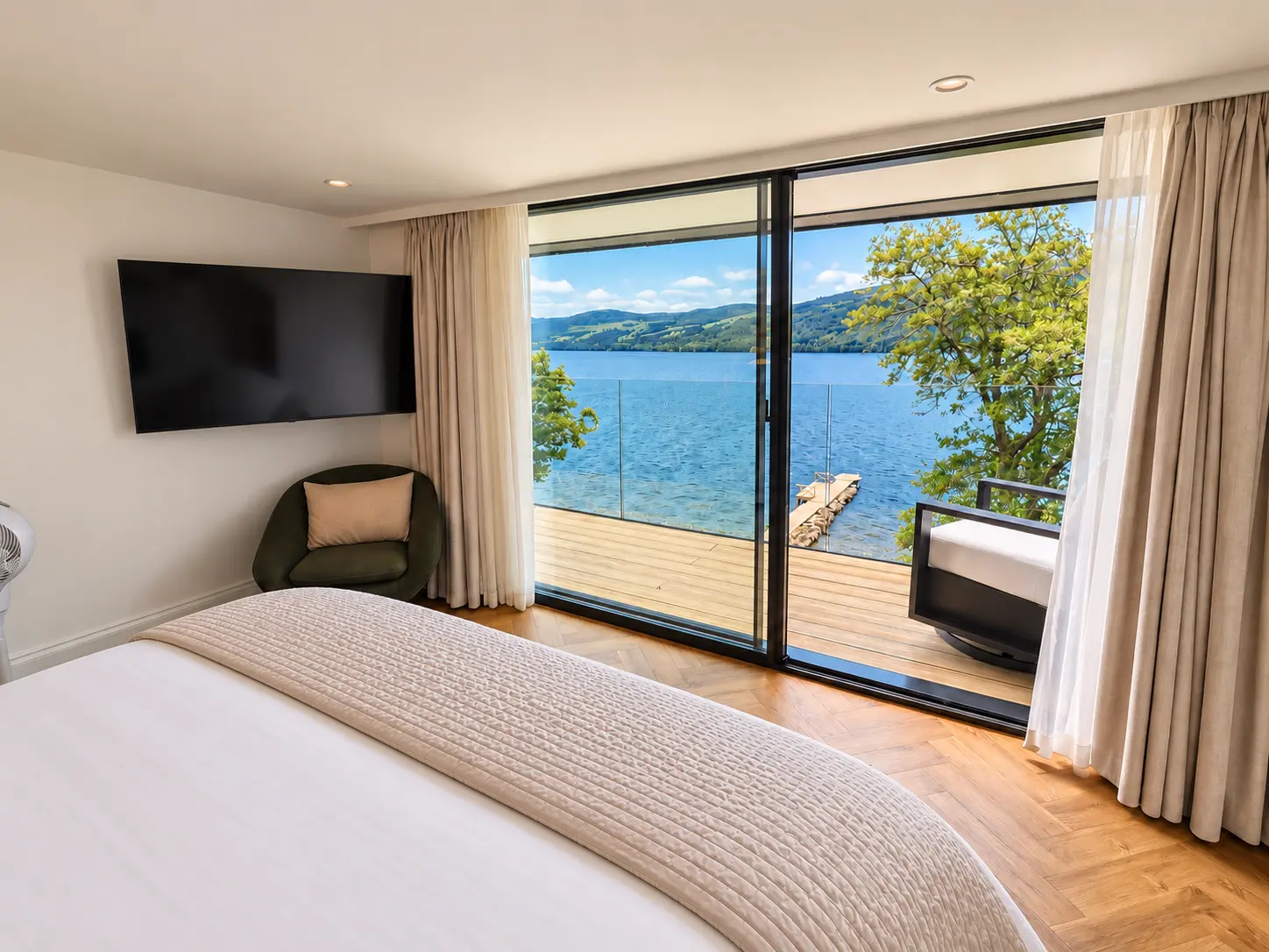Bedroom opening onto a balcony with views across Loch Tay and the private jetty below