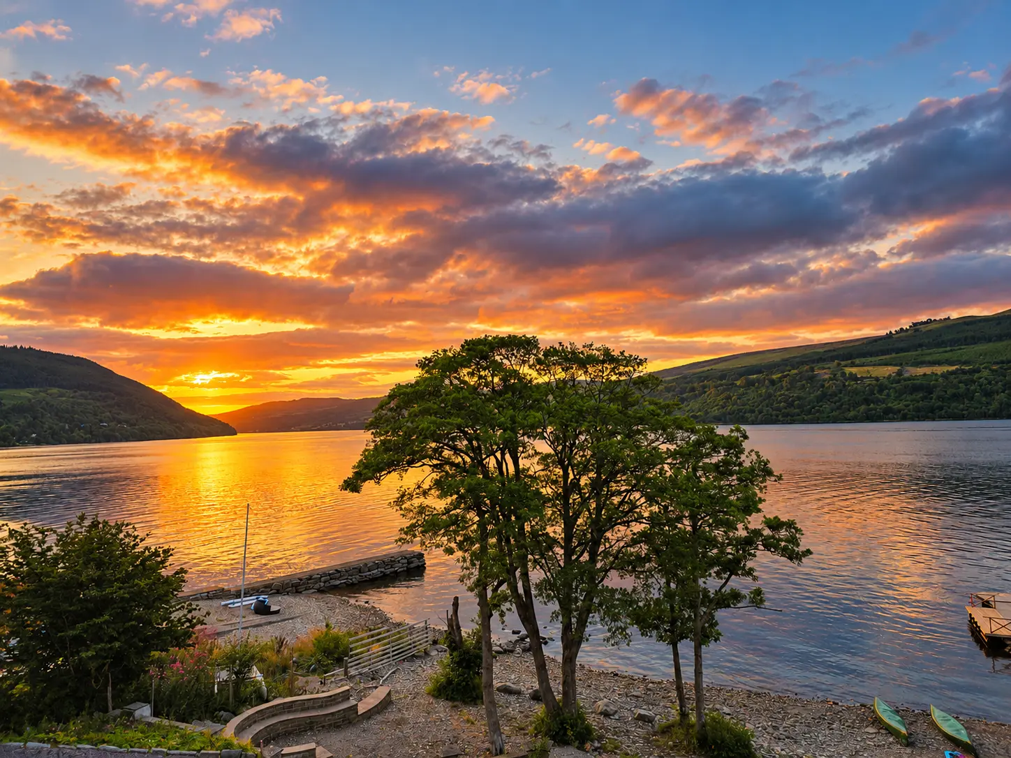 Golden sunset over Loch Tay seen from the house, with the shoreline, jetty and canoes below
