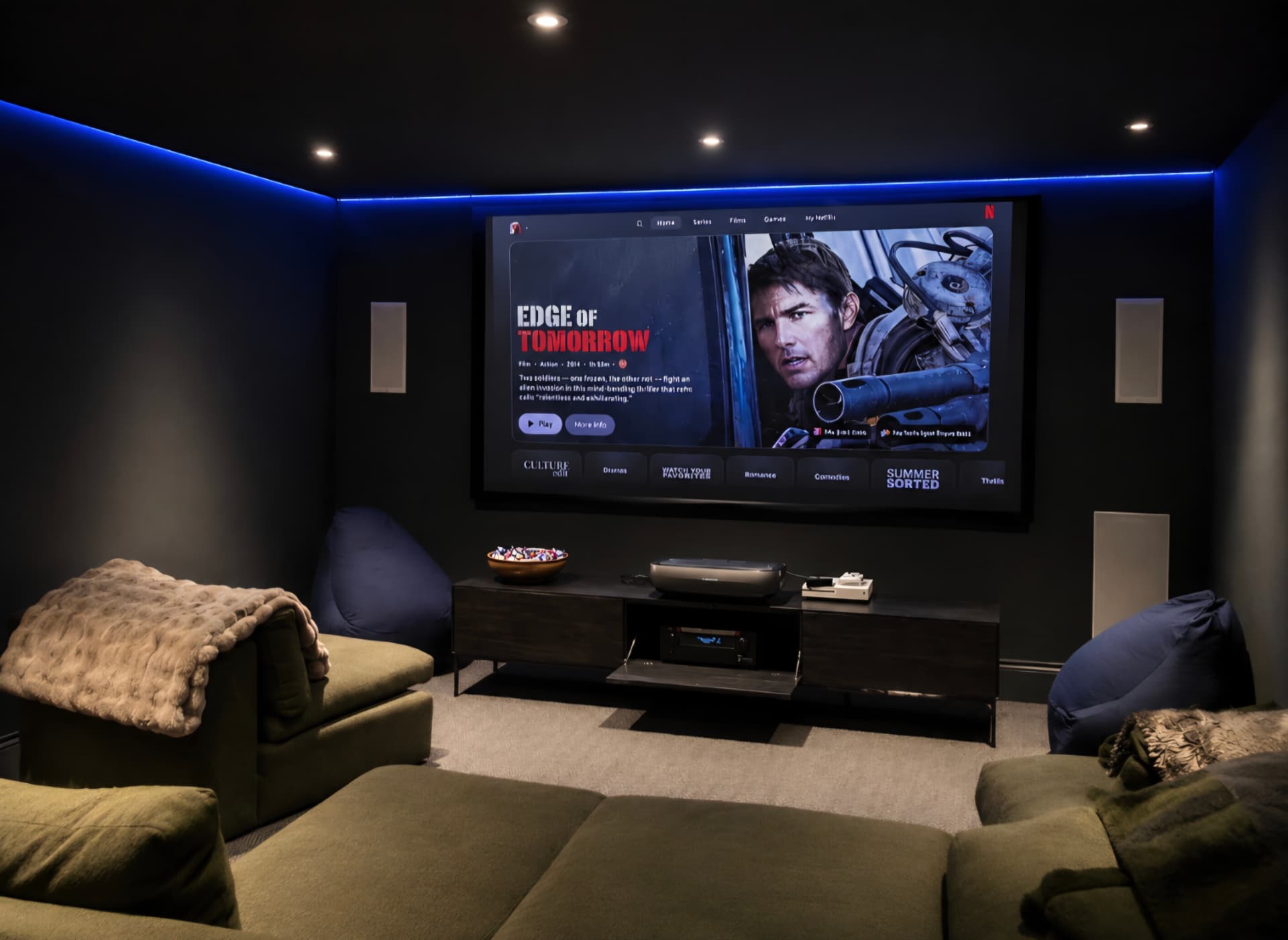 Cinema room with a large projection screen, surround sound and loungers beneath a blue-lit ceiling