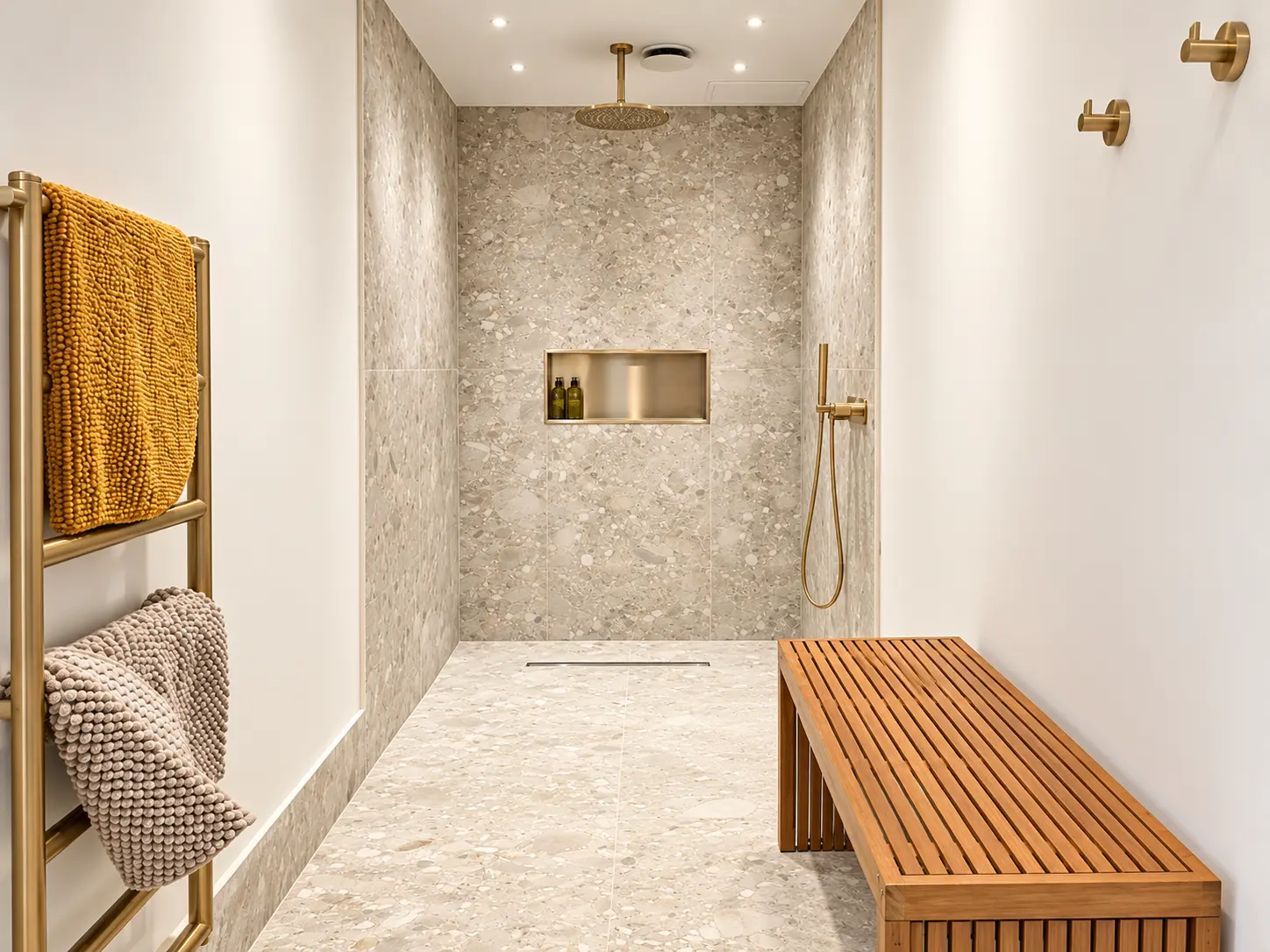 Gym changing room with walk-in terrazzo shower, brushed brass shower fittings, heated towel rail and timber bench