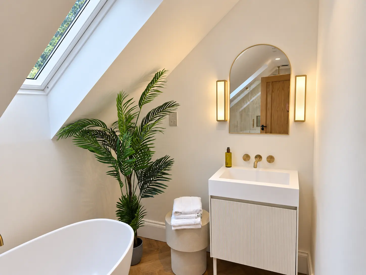 En-suite basin with arched brass mirror and wall lights